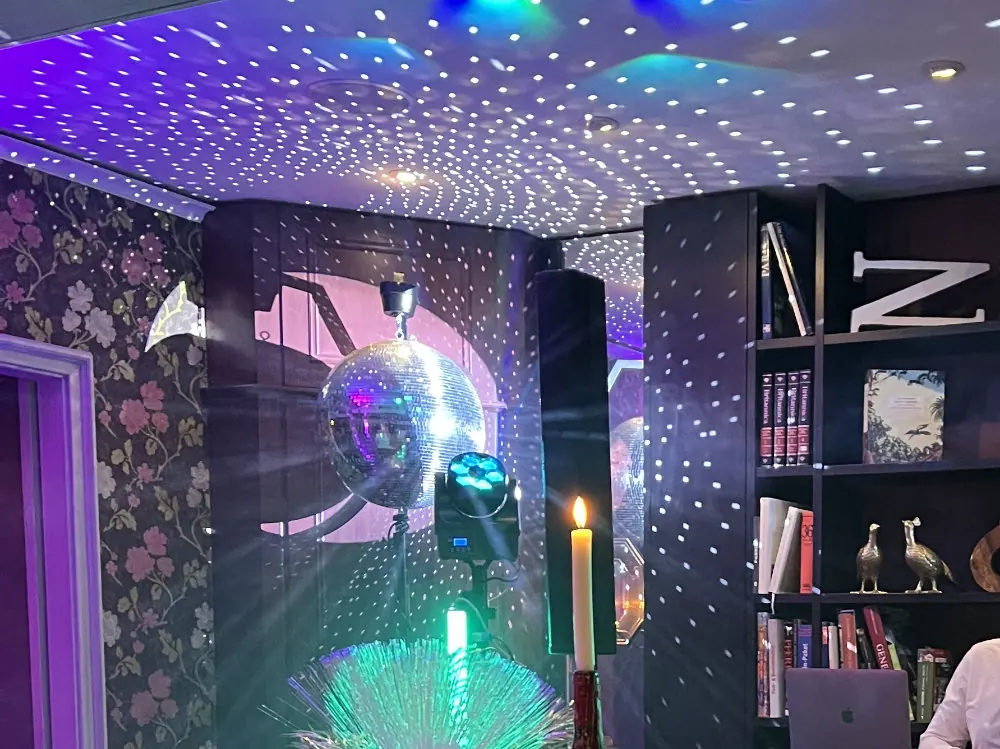 Große Discokugel auf Ständer, die tausende Lichtpunkte an Decke und Wände wirft